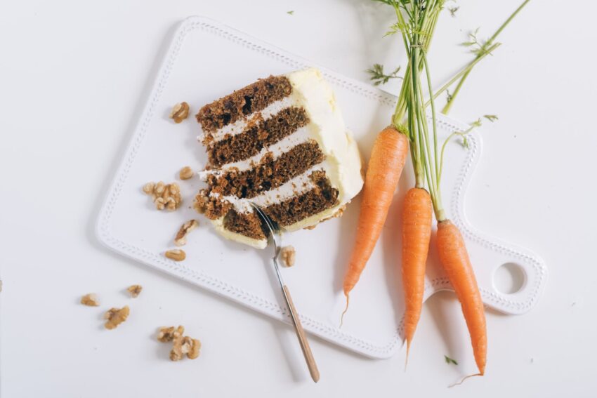 orange carrots and white icing cake on white chopping board