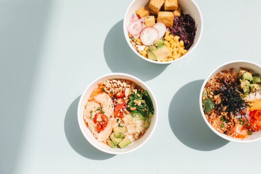 overhead shot of poke bowls on a blue surface