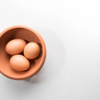 three brown eggs in bowl