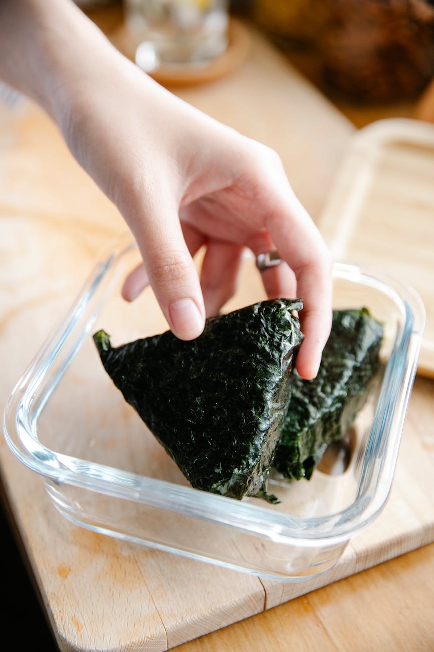 unrecognizable cook putting onigiri into container