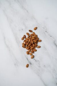 A minimalist flat lay of almonds scattered over a marble-textured background.