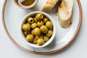 Delicious green olives with rustic bread on a ceramic plate, offering a Mediterranean culinary taste.