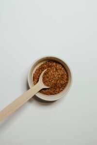 Top view of flax seeds in a bowl with a wooden spoon against a white background.