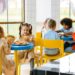 Group of children eating together at a school cafeteria, sharing joy and food.