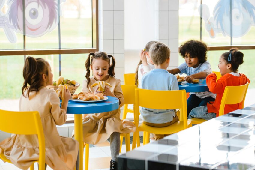 Group of children eating together at a school cafeteria, sharing joy and food.