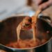 crop person preparing delicious spaghetti with meatballs in kitchen