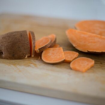 Close-up of sliced sweet potato on a wooden cutting board, perfect for cooking inspiration.