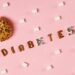 Creative depiction of diabetes with a donut, sugar cubes, and letters on a pink background.
