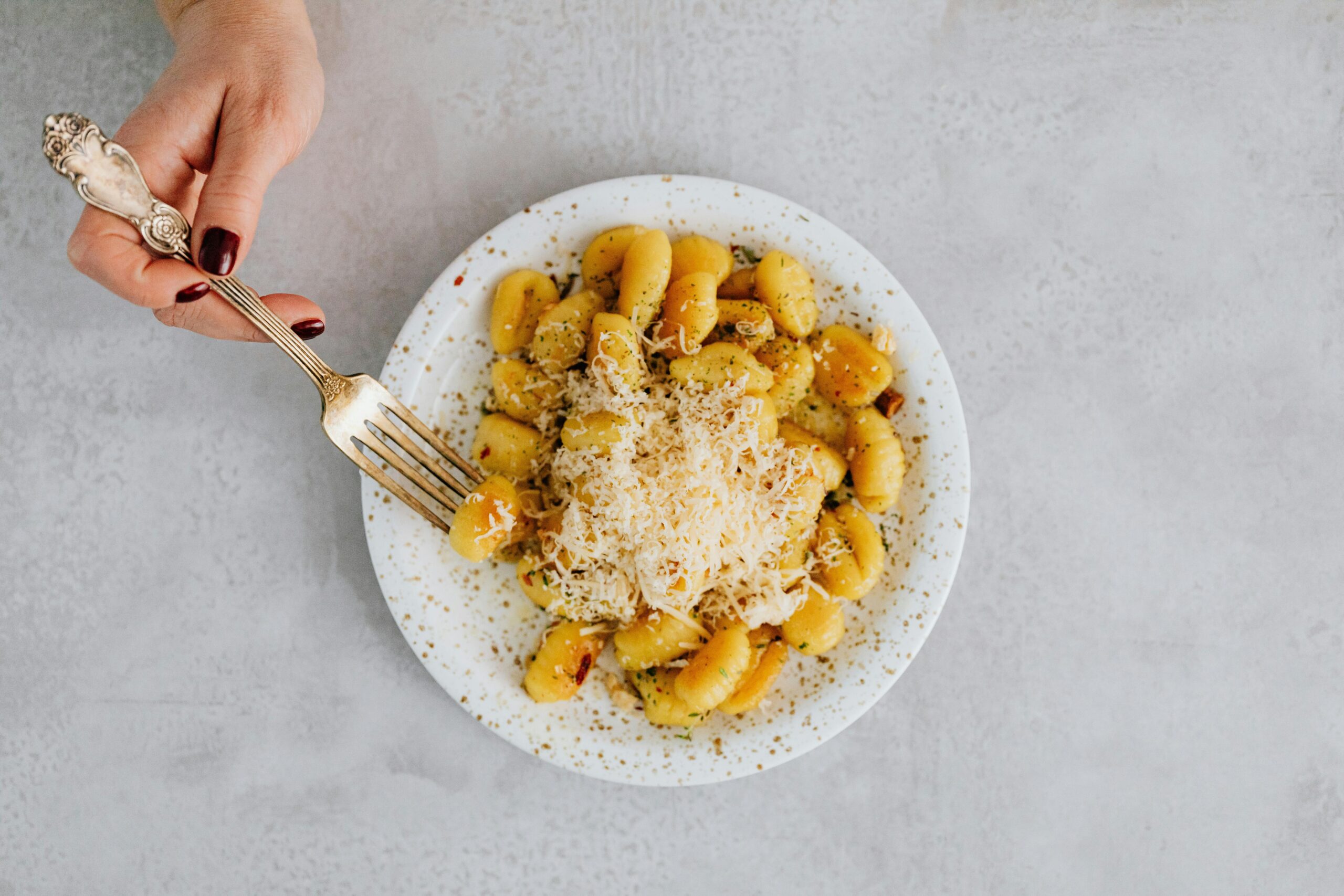 Delicious gnocchi topped with grated parmesan served on a white ceramic plate.
